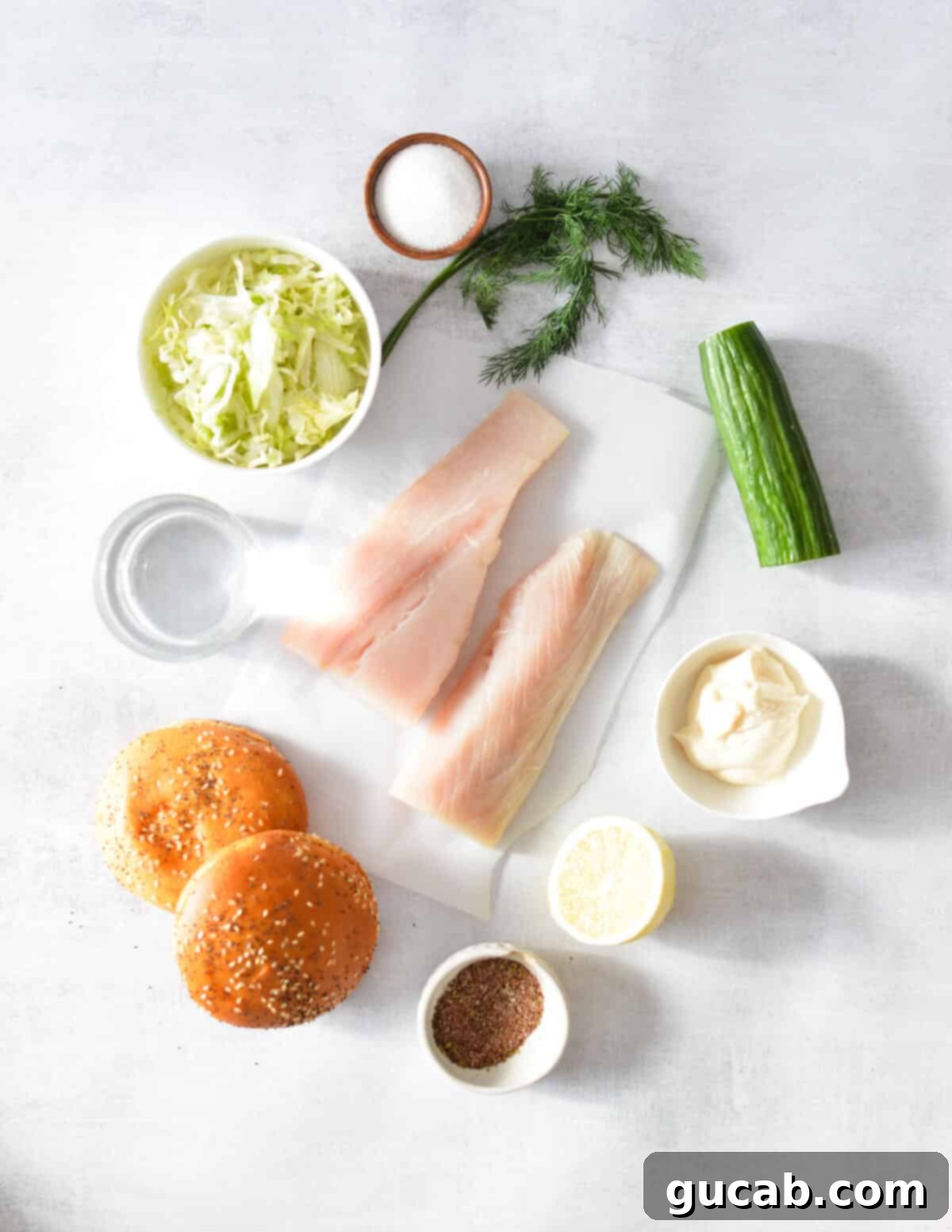 Key ingredients for a Mahi Mahi sandwich: mahi mahi fillets, English cucumber, shredded lettuce, mayonnaise, brioche buns, fresh lemon, fresh dill, and blackening spices.