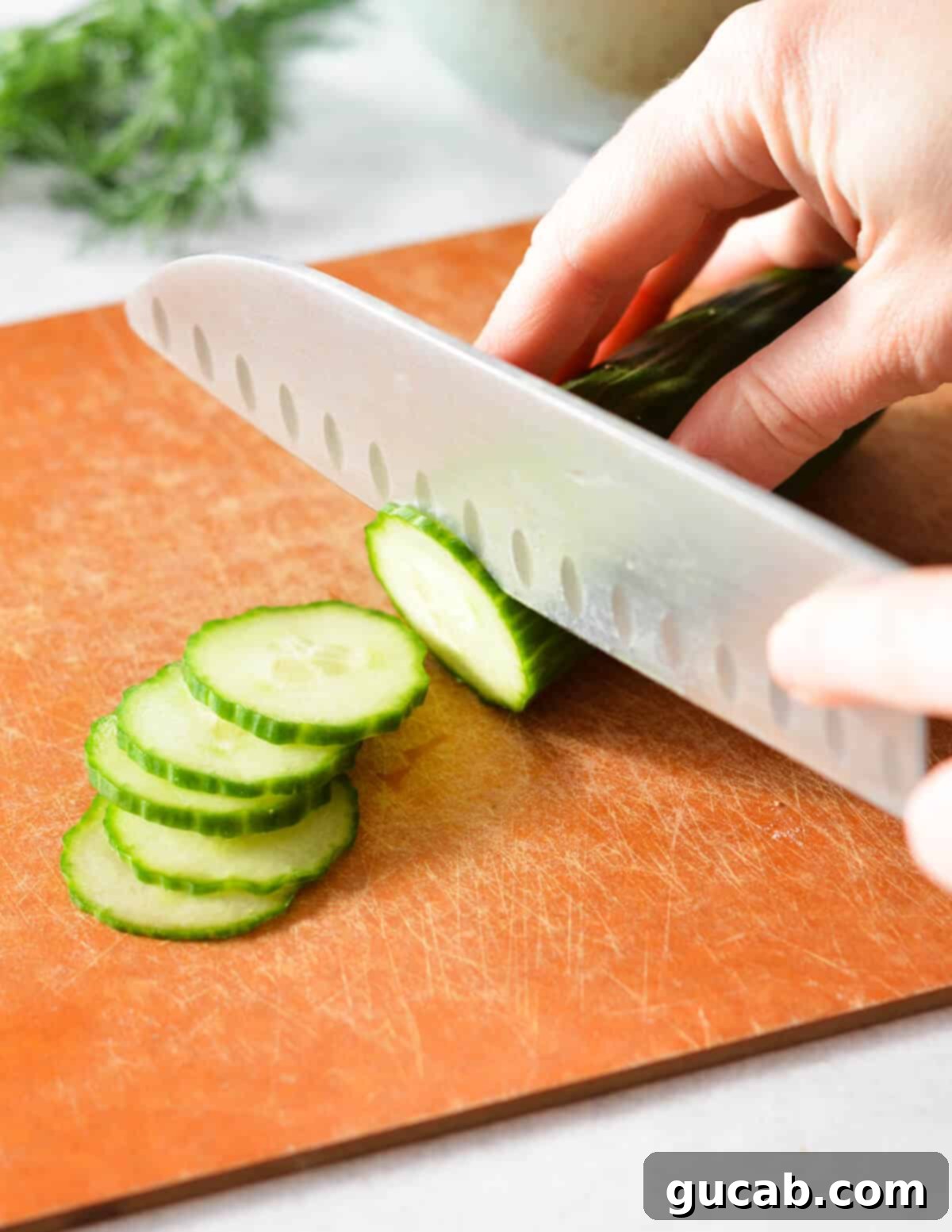 A hand expertly cutting an English cucumber into thin slices for homemade pickles.