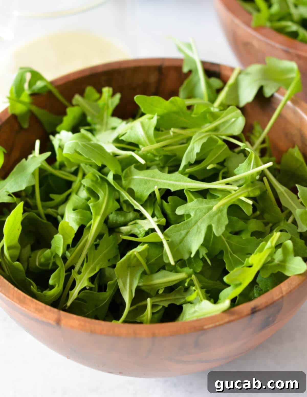 A large bowl filled with fresh baby arugula leaves, ready for salad preparation.