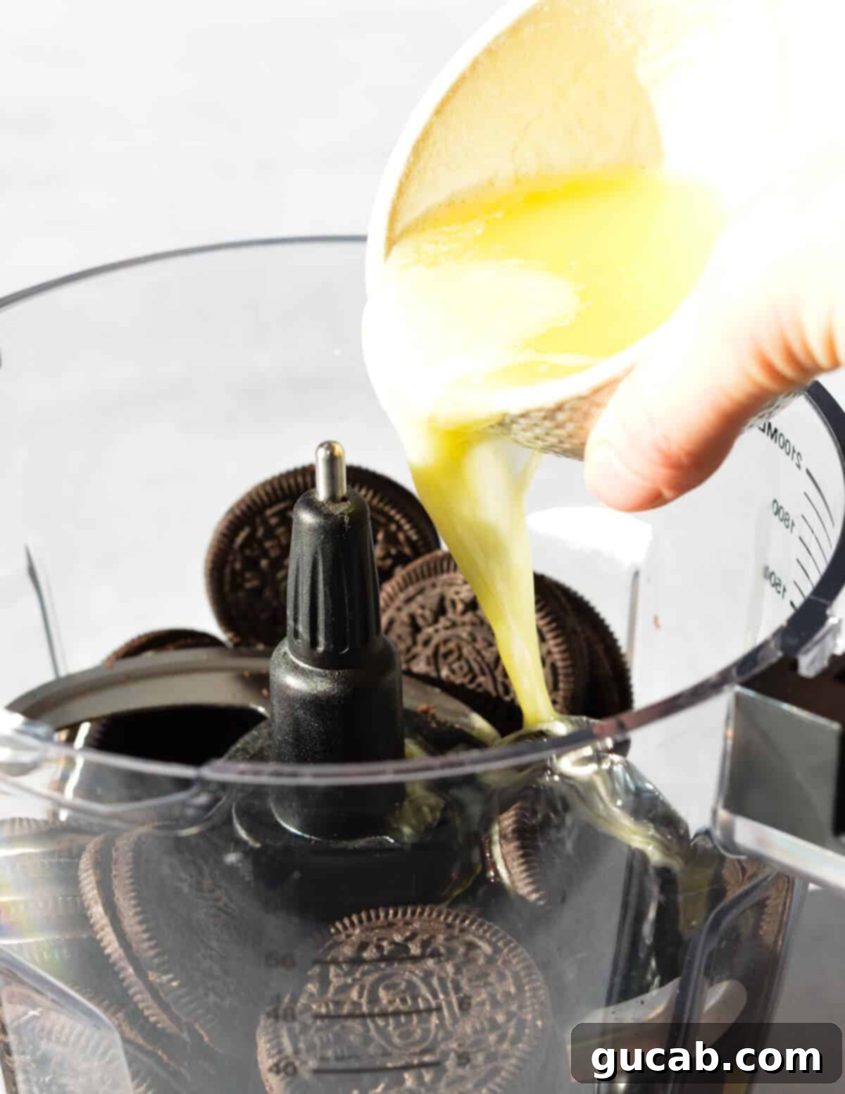 The Ultimate Gluten-Free Oreo Pie Crust 6 pouring butter into a food processor with Oreos.