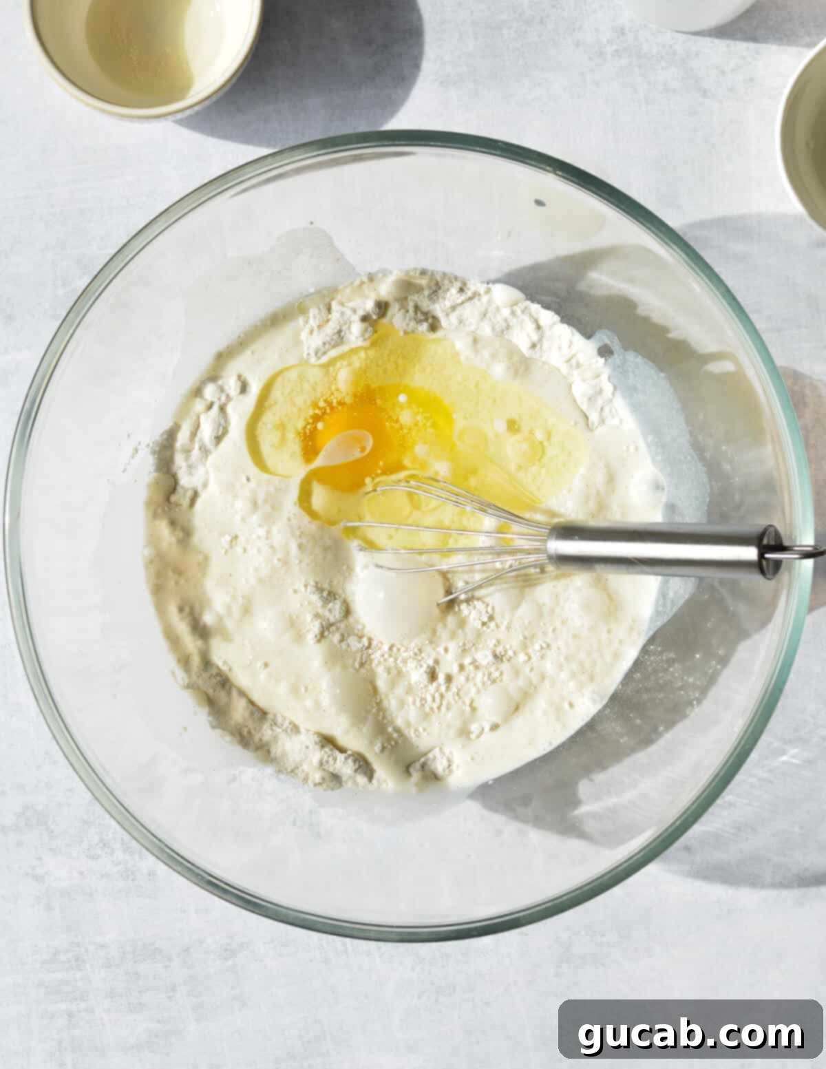 a bowl of flour with egg and milk in it. 