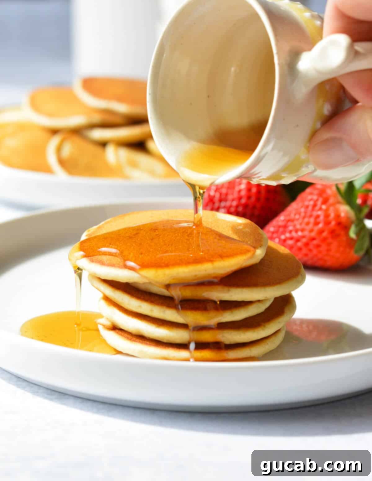 pouring syrup on a stack of pancakes
