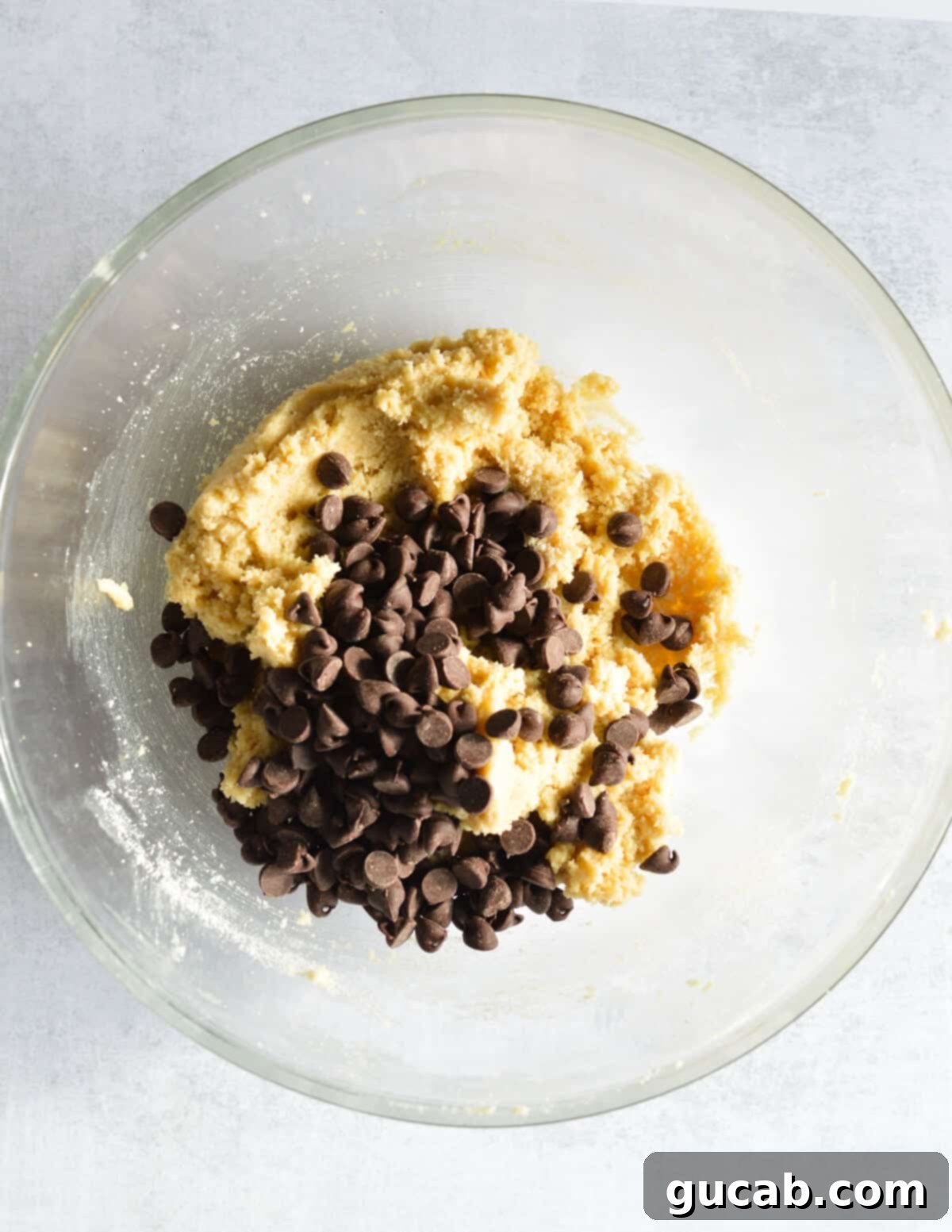 Ultimate Almond Flour Chocolate Chip Cookies 10 a bowl of almond flour cookie dough with chocolate chips on top. Ready for mixing.