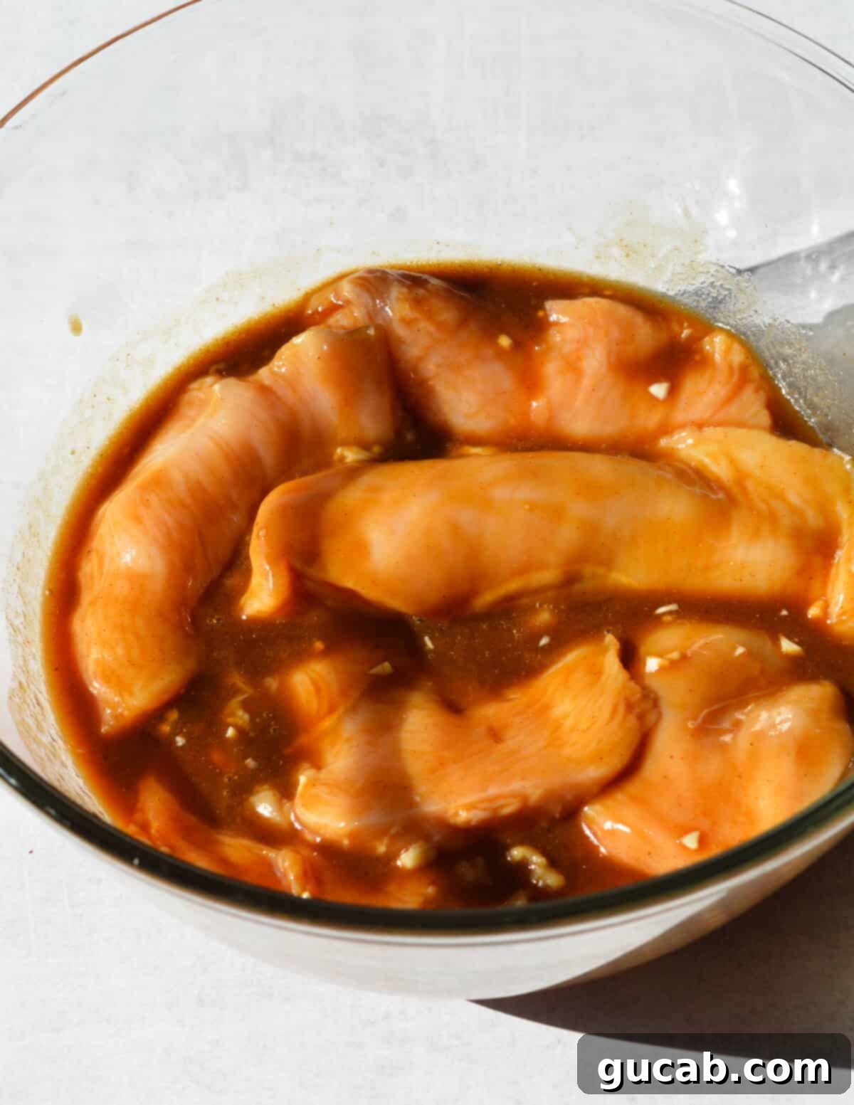 A bowl of chicken breasts thoroughly coated in the rich balsamic marinade, ready for refrigeration and flavor infusion.