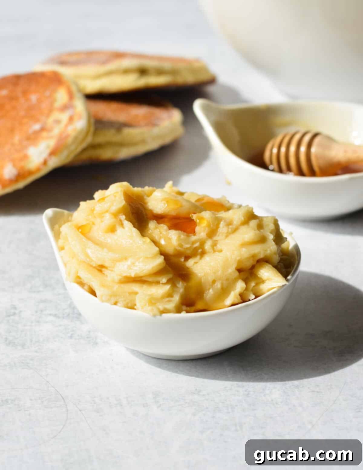 A small bowl of fluffy honey butter, topped with an extra swirl of honey, ready for serving.