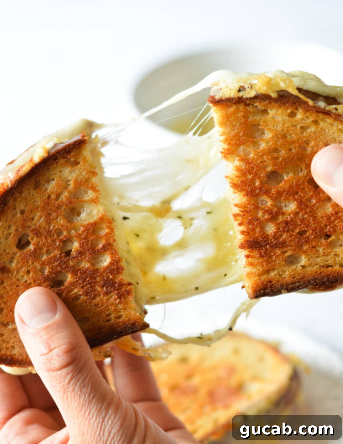 hands pulling a grilled cheese sandwich apart. 