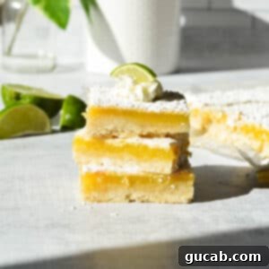 A stack of perfectly golden gluten-free key lime bars, dusted with powdered sugar, ready to be enjoyed.
