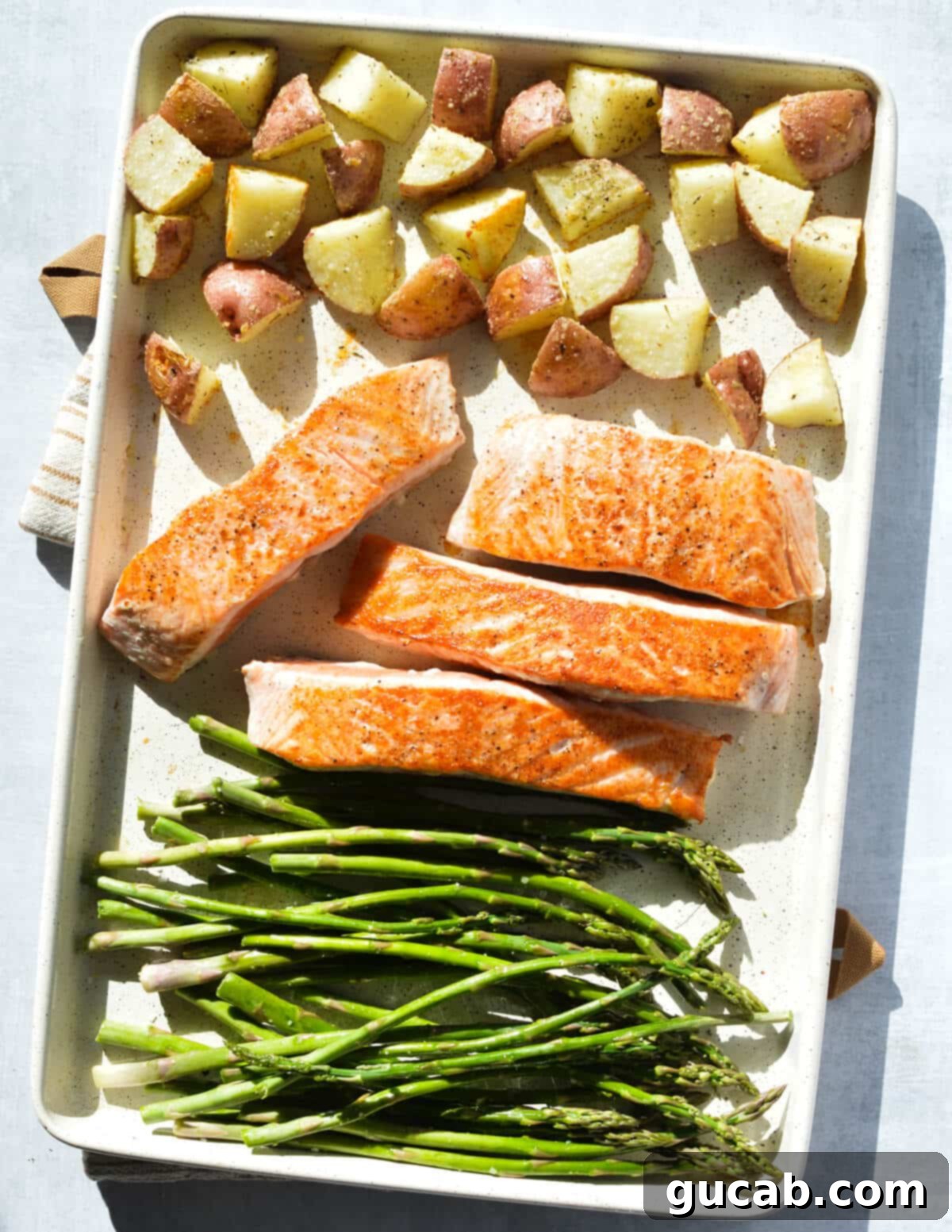 roasted potatoes, seared salmon fillets, and asparagus on a sheet pan. 