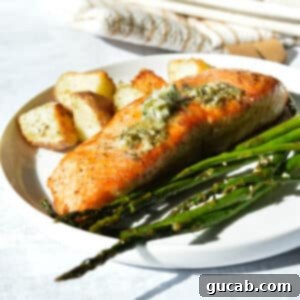 salmon with herb butter, asparagus, and potatoes on a plate.