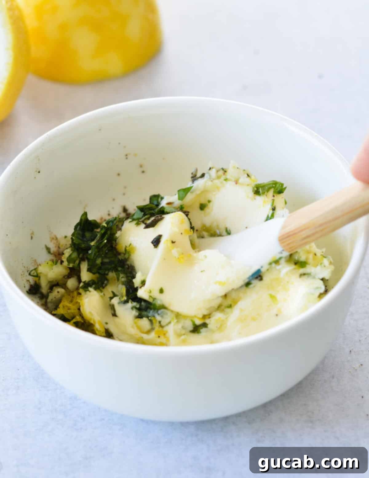 mashing butter and herbs with a spatula in a bowl. 