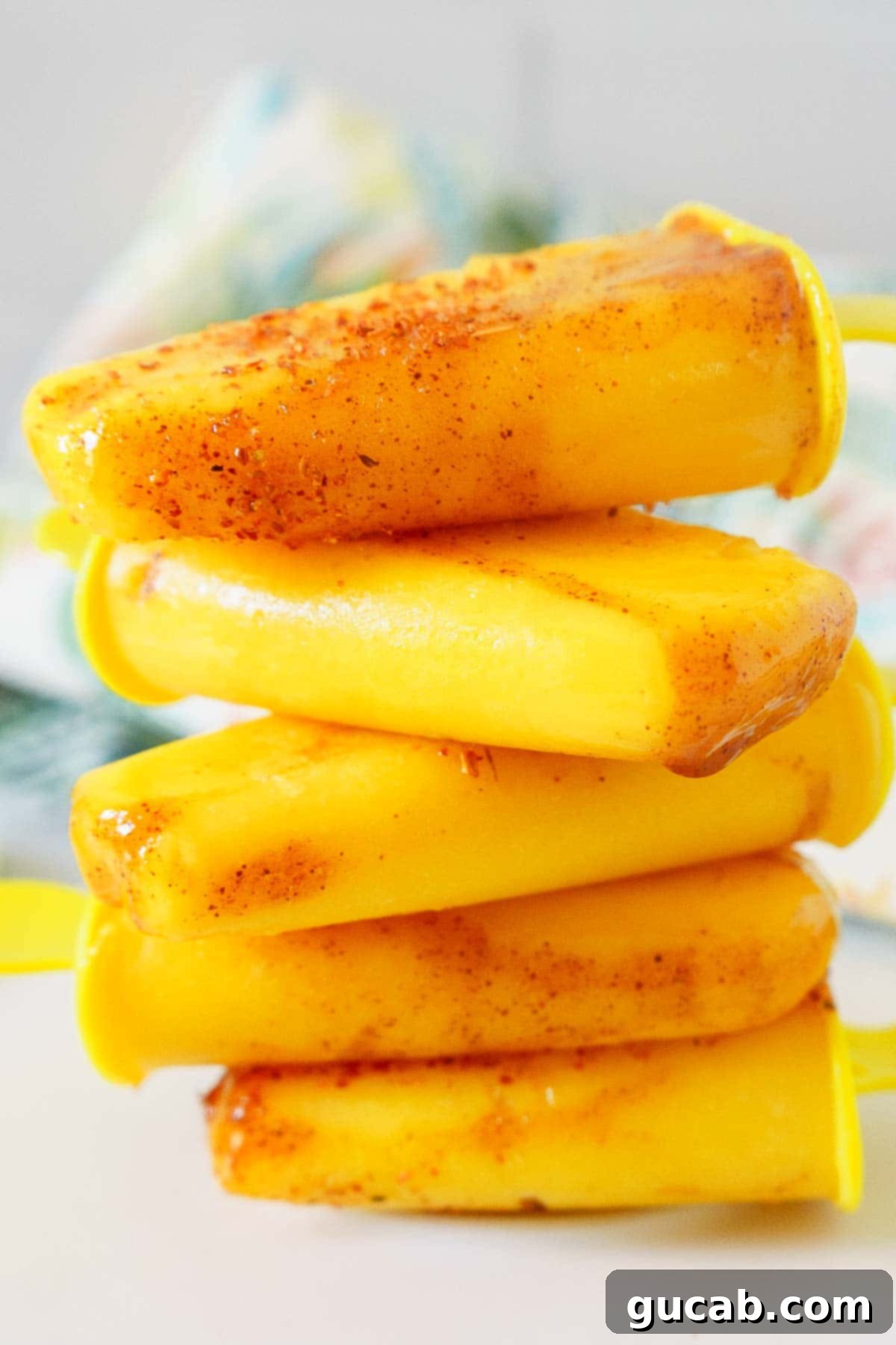 Sun-Kissed Mango Creations 15 A stack of vibrant mangonada popsicles, sweet, sour, and spicy.