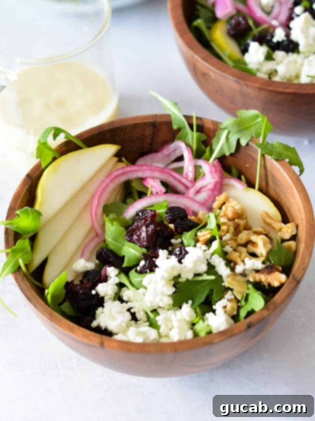 A fresh and vibrant pear arugula salad, featuring tender greens, sweet cranberries, creamy goat cheese, and juicy pear slices, dressed with a light vinaigrette.