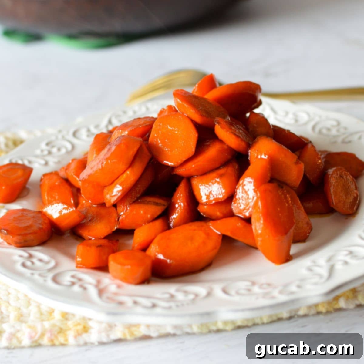 A beautiful plate of bright orange maple glazed carrots, perfectly tender and glistening with a sweet, sticky coating.