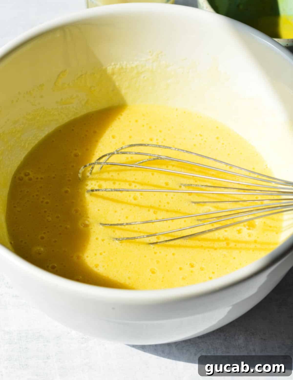 A bowl filled with the unbaked lemon filling mixture, smooth and bright yellow.