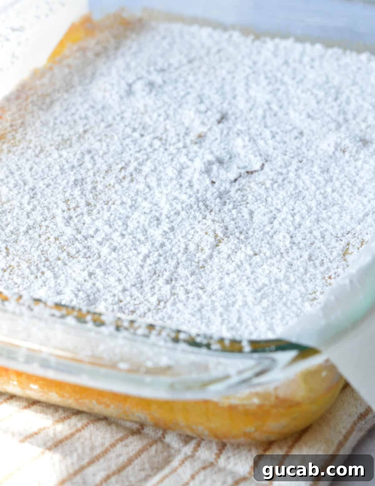 Freshly baked gluten-free lemon bars in the pan, generously dusted with powdered sugar.