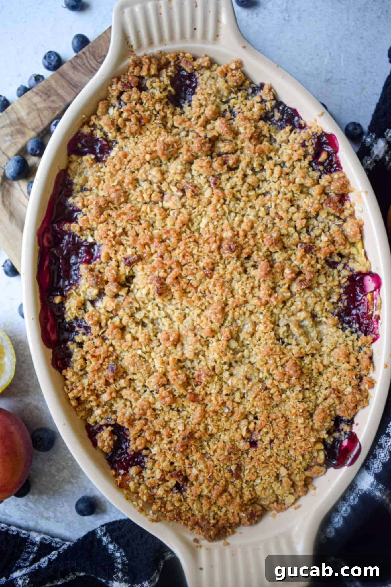 A vibrant blueberry peach crisp baking dish, showcasing the bubbling fruit filling and golden oat topping, ready for serving.