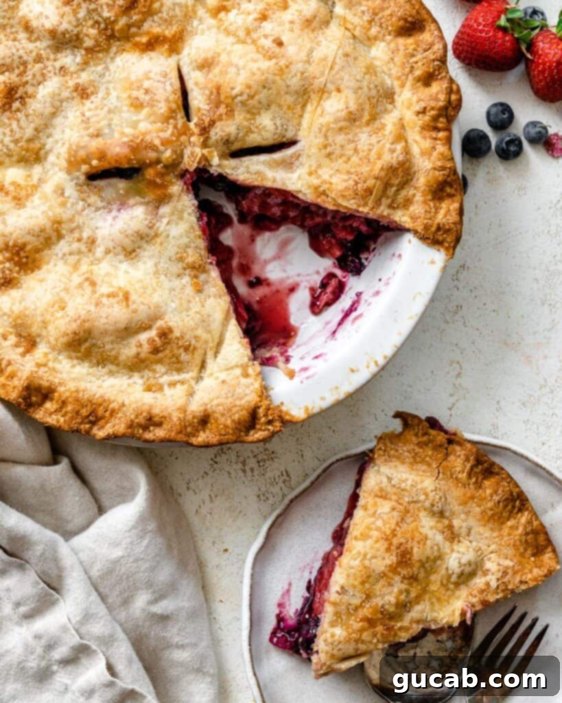 A vibrant strawberry blueberry pie with a slice carefully removed, revealing the juicy fruit filling.