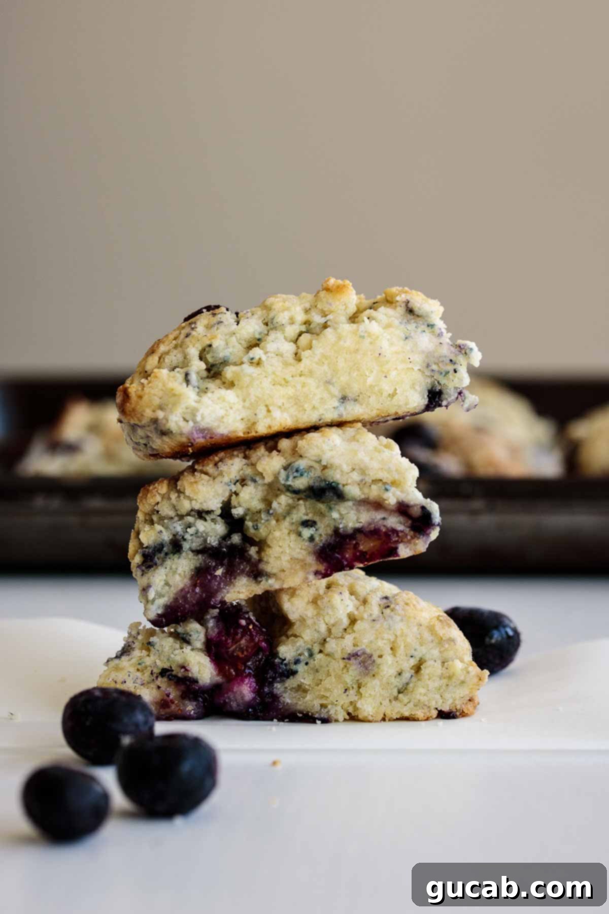 A stack of golden-brown Starbucks copycat blueberry scones, glistening with a lemon glaze.