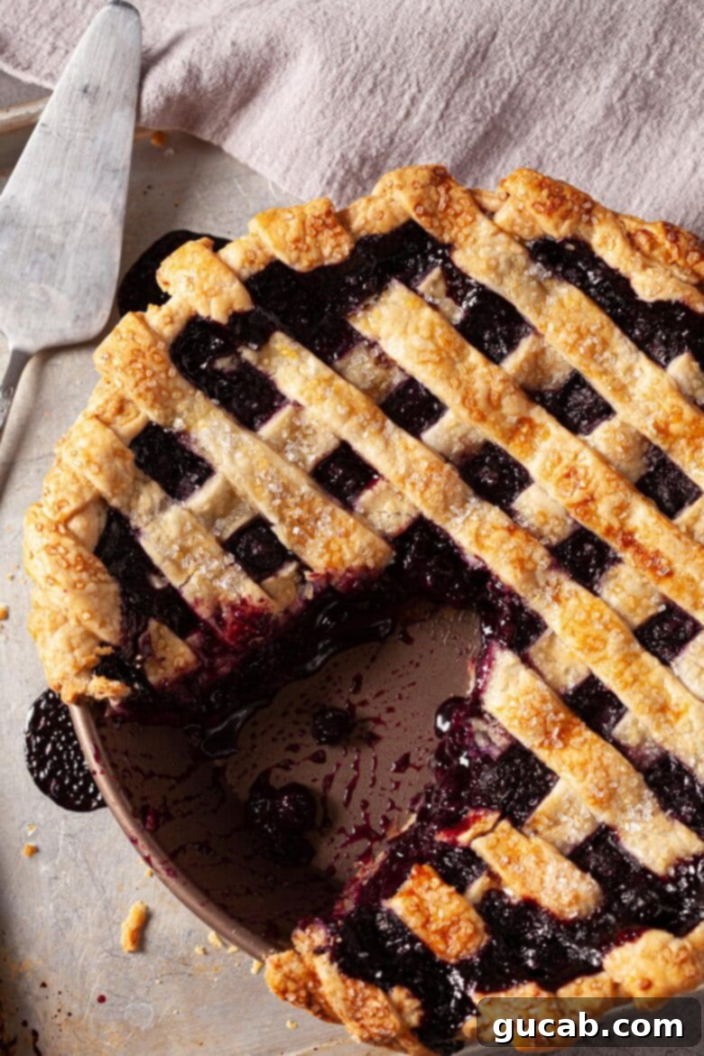 A classic blueberry pie, golden-brown and perfectly baked, with a tempting slice already removed.