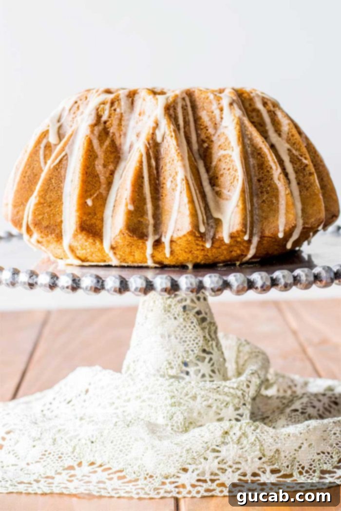 A beautifully baked eggnog bundt cake, elegantly presented on a cake stand, drizzled with a sweet eggnog glaze.