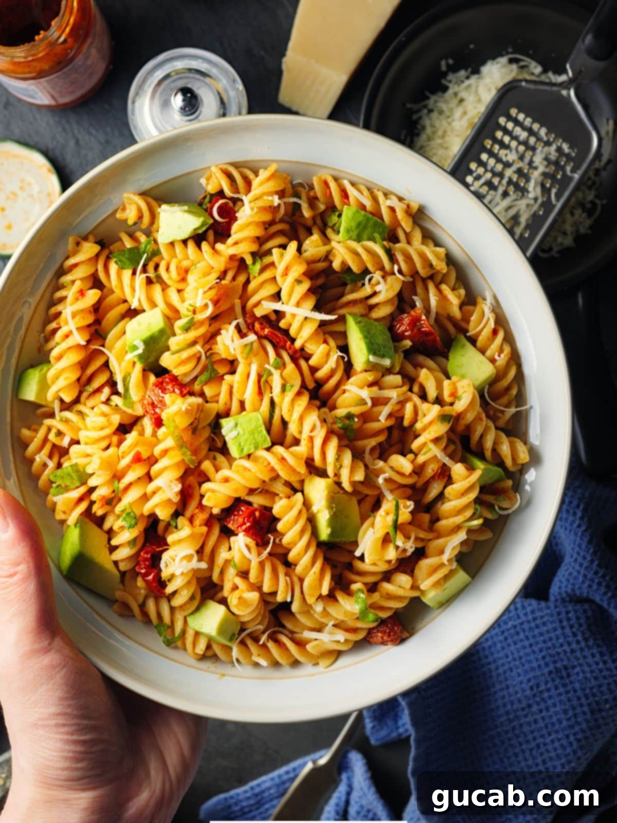 A vibrant bowl of classic pasta salad, featuring colorful pasta, fresh vegetables, and a sprinkle of Parmesan cheese on the side.