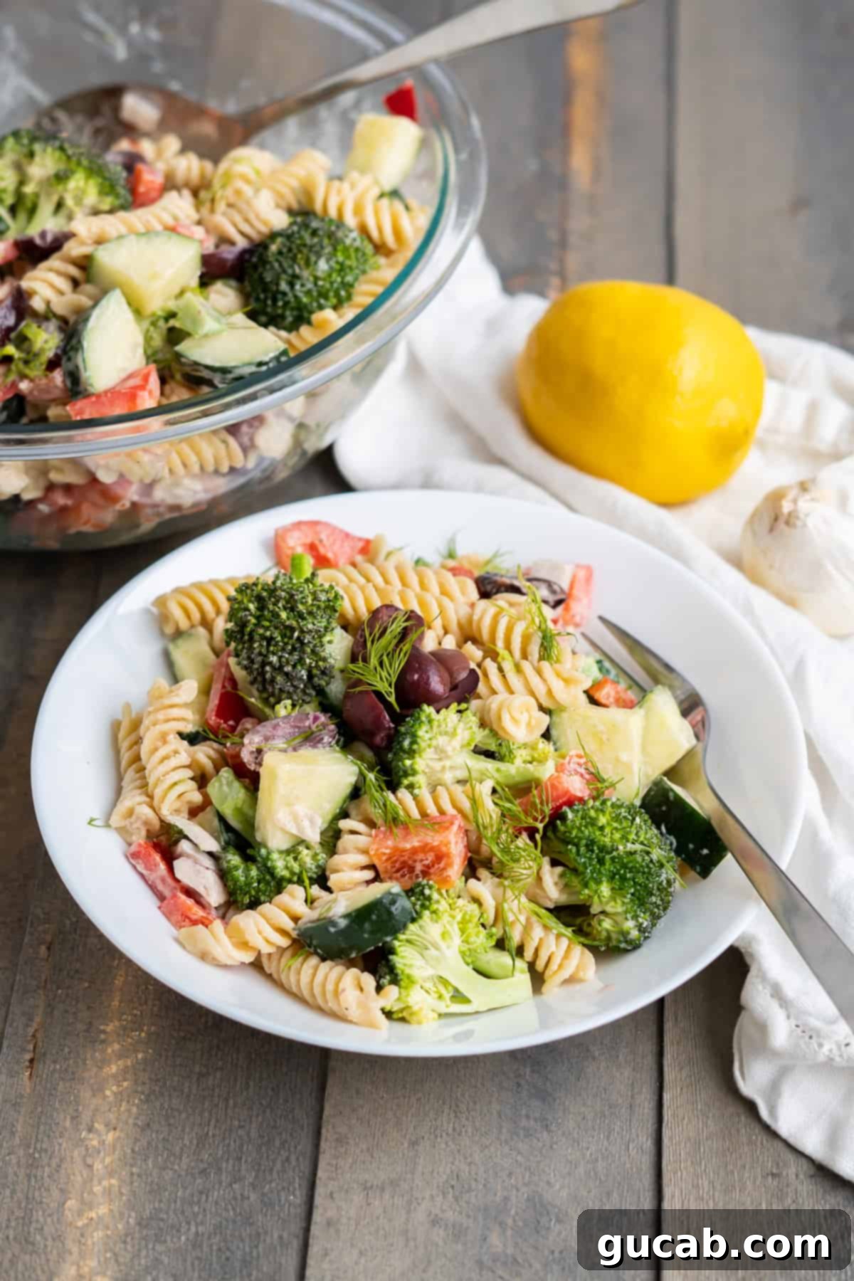 A creamy and fresh bowl of Greek tahini pasta salad, highlighting its rich, savory dressing and vibrant vegetables.