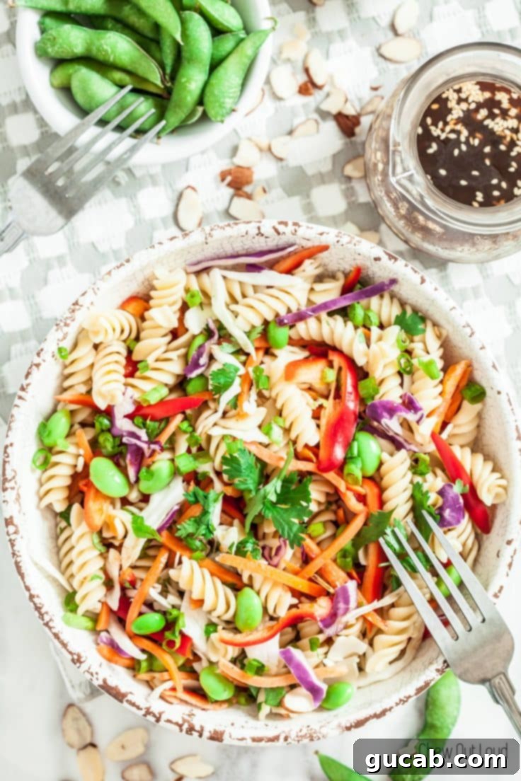 The Ultimate Collection of Irresistible Pasta Salads 9 A vibrant bowl of Asian pasta salad, generously coated in a glossy sesame ginger dressing, with various vegetables visible.