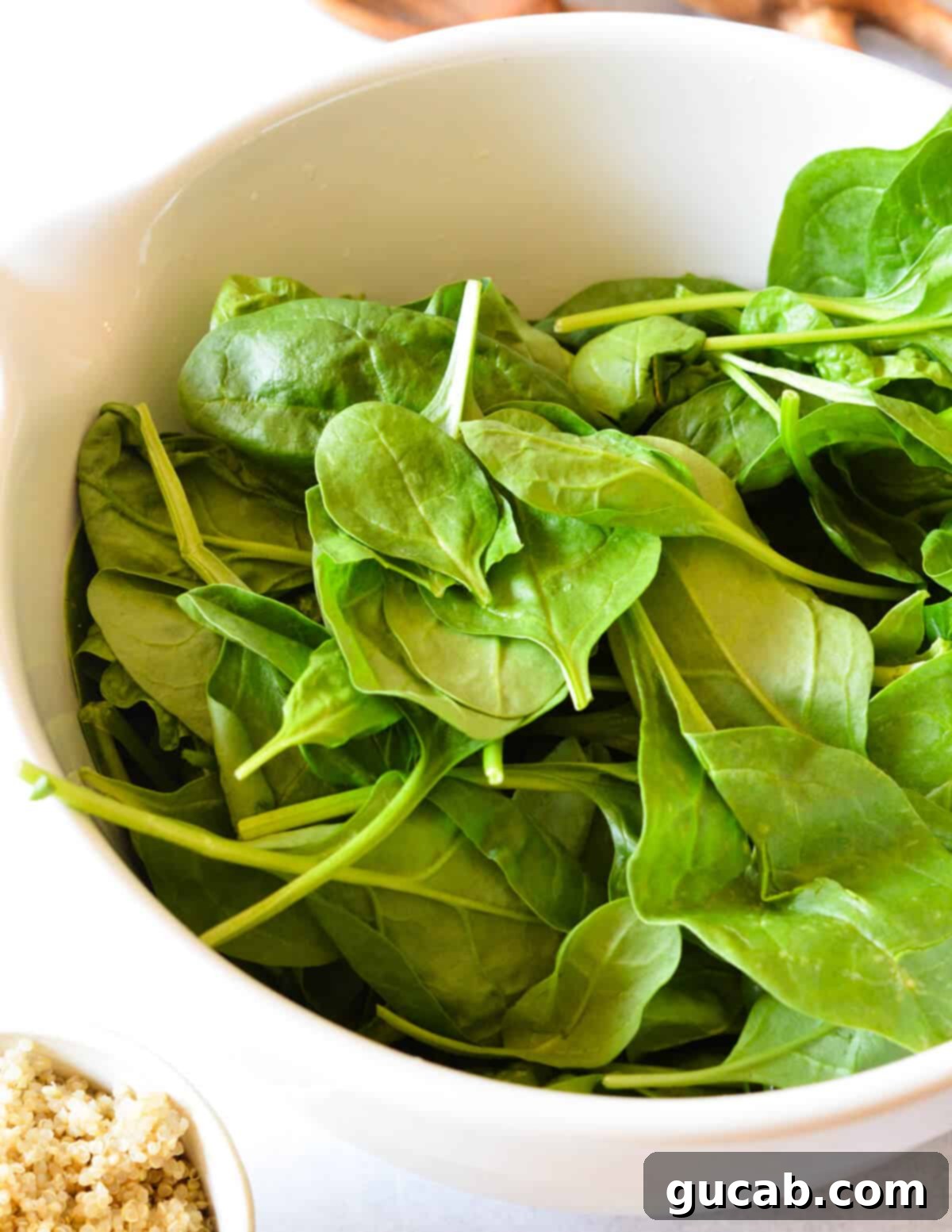 A close-up shot of a bowl filled with vibrant green baby spinach leaves, ready for the other salad ingredients.