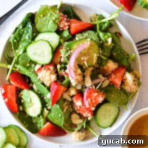 Vibrant Strawberry Cucumber Salad 8 A vibrant spinach salad with a mix of strawberries, cucumber, and pickled onions, ready to be served.