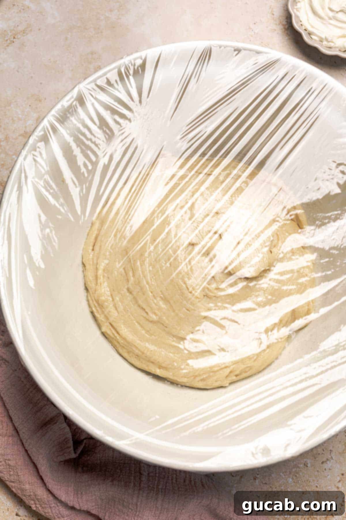Irresistible Gluten-Free Cinnamon Rolls 11 Gluten-free dough freshly placed in a large, greased bowl and covered with plastic wrap, ready for its initial two-hour rise.