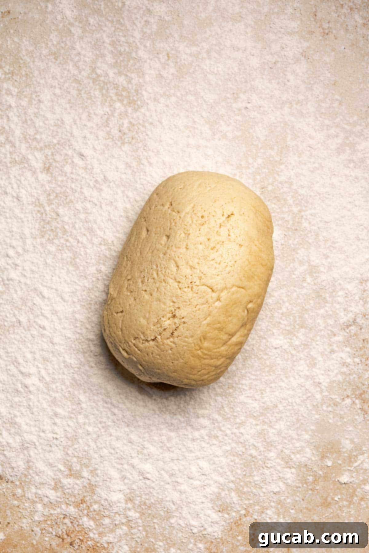 Irresistible Gluten-Free Cinnamon Rolls 13 Gluten-free dough placed on a work surface, generously dusted with gluten-free flour to prevent sticking during rolling.