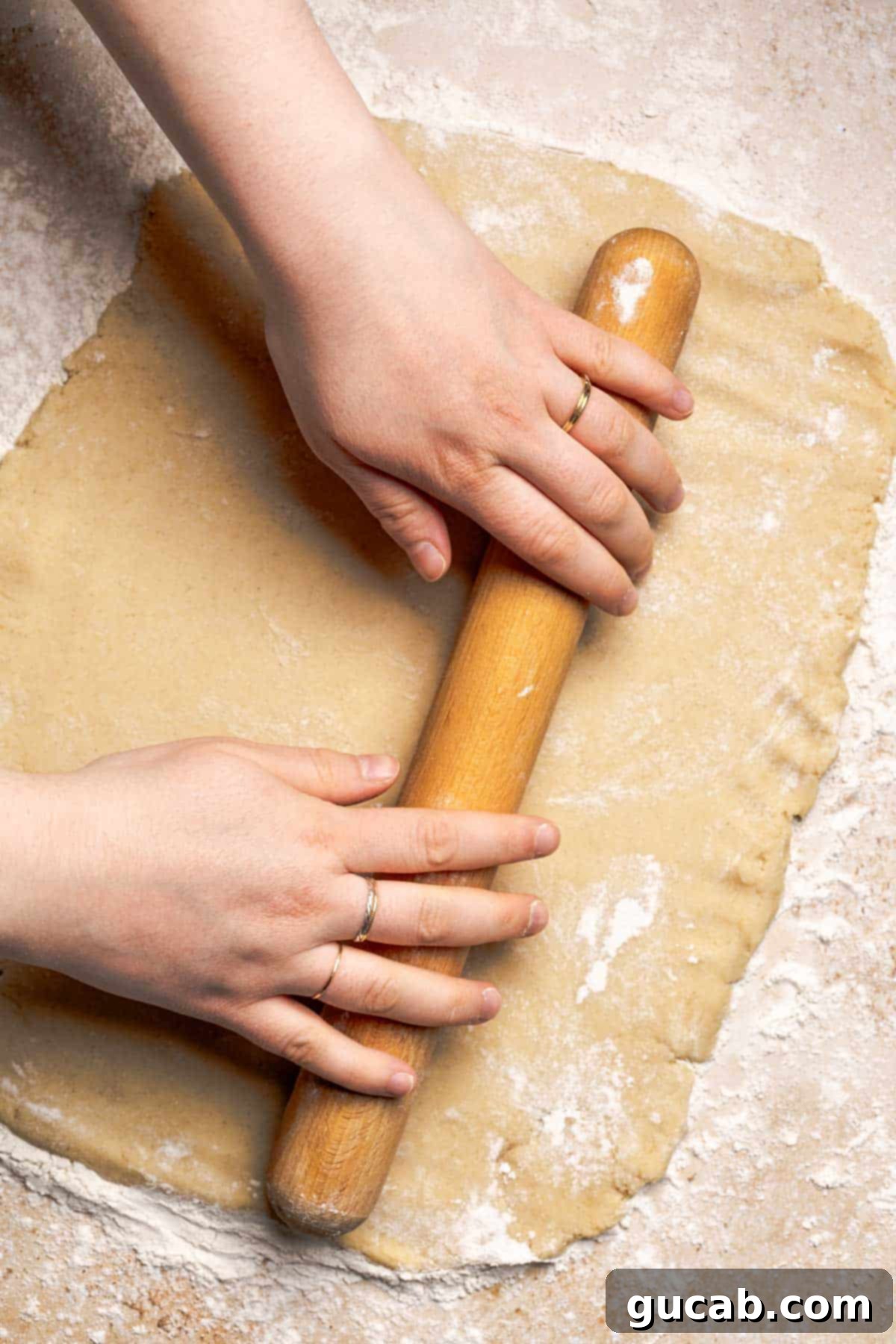Irresistible Gluten-Free Cinnamon Rolls 14 Hands using a rolling pin to carefully roll out the floured gluten-free cinnamon roll dough into a rectangular shape.