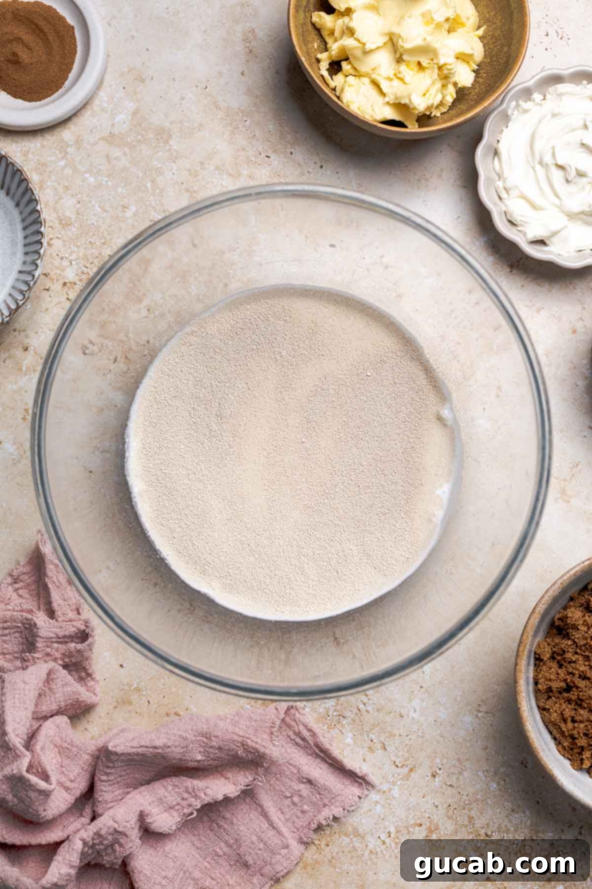 Irresistible Gluten-Free Cinnamon Rolls 5 A bowl containing warm milk, active dry yeast, and a small amount of sugar, before activation, showing the initial state of the ingredients.