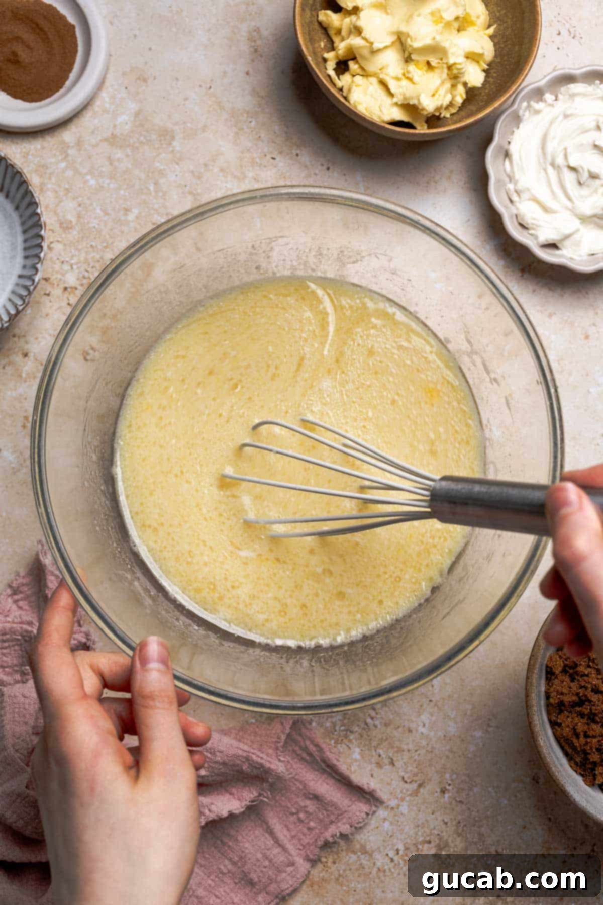 Irresistible Gluten-Free Cinnamon Rolls 8 The bowl of milk, yeast, eggs, oil, and sugar after being thoroughly whisked together, creating a uniform liquid mixture for the dough.