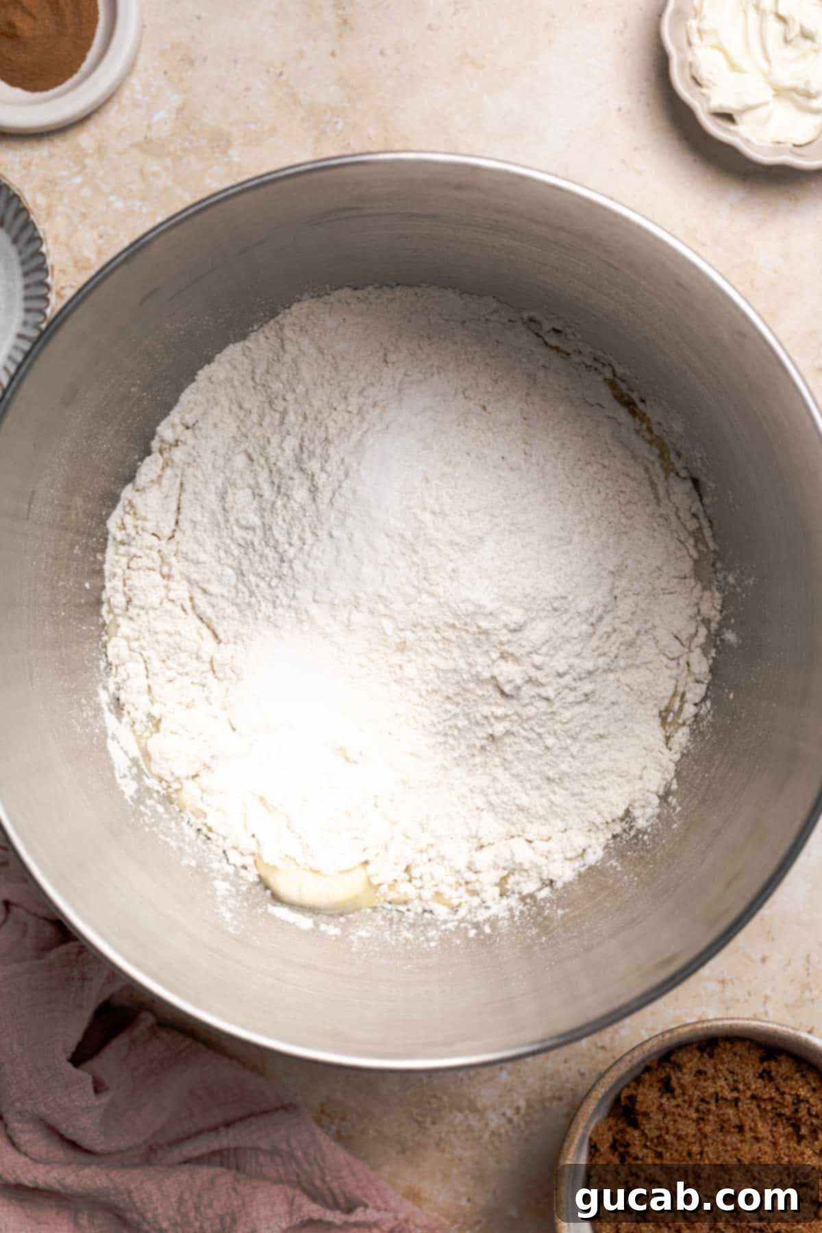 Irresistible Gluten-Free Cinnamon Rolls 9 Gluten-free flour, salt, baking soda, and cream of tartar added to the wet ingredients in the bowl of a stand mixer, ready for mixing.