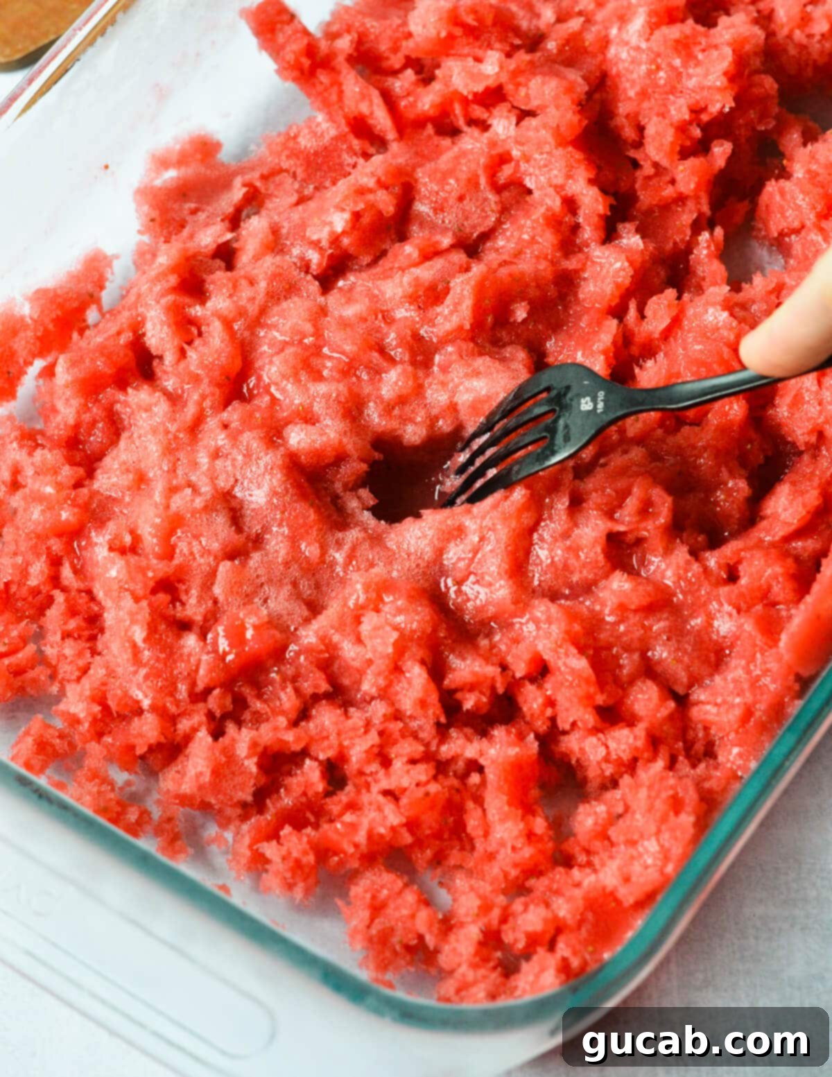 Strawberry Passion Zing 8 fork scraping strawberry granita in a baking dish.