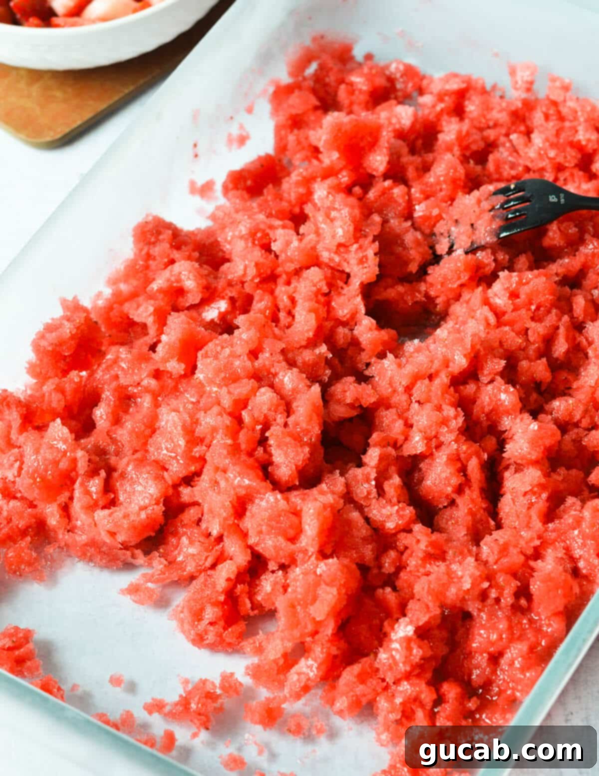 Strawberry Passion Zing 9 fork scraping strawberry granita in a baking dish.