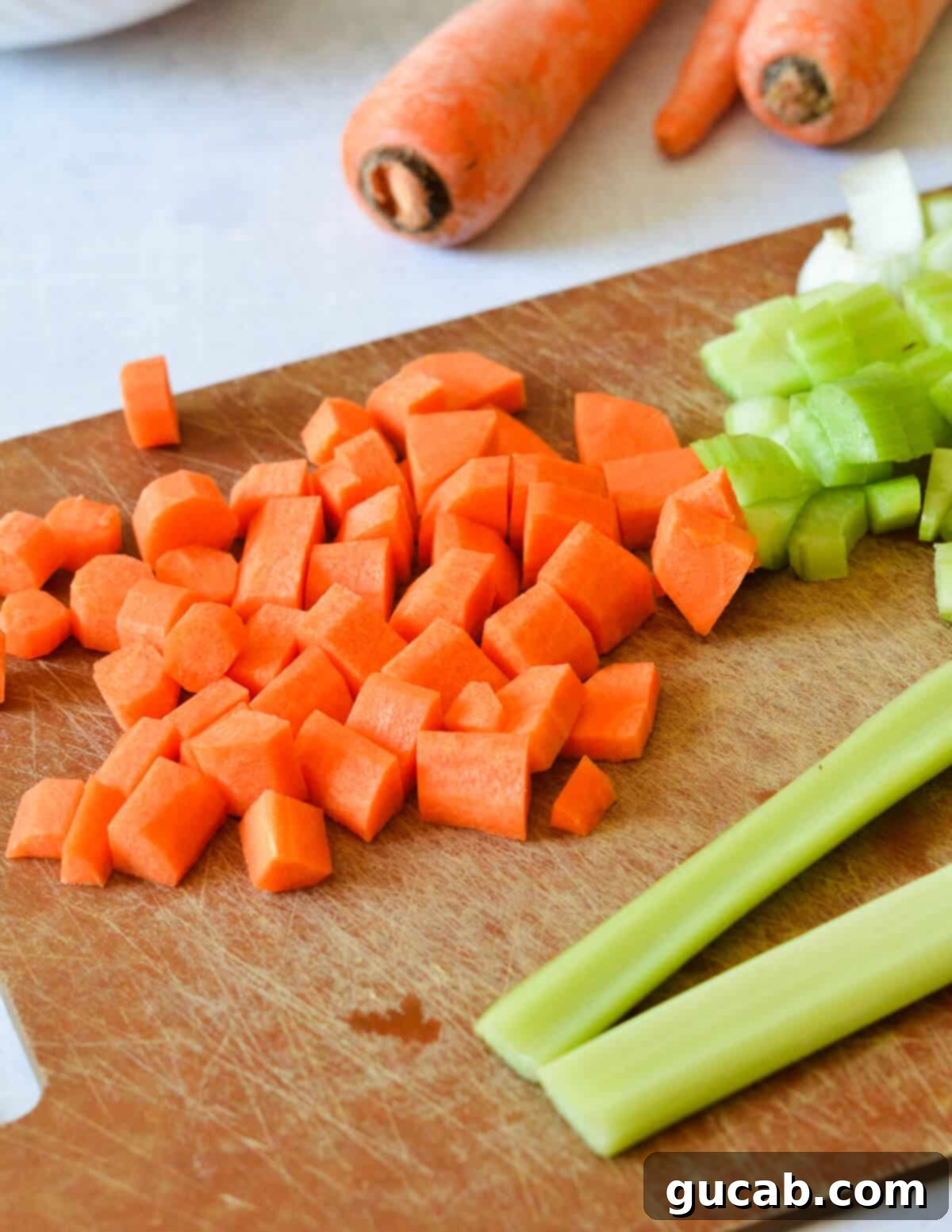 Vibrant Veggie Noodle Bowl 5 Freshly diced carrots and celery neatly arranged on a wooden cutting board, prepped and ready for the soup base.