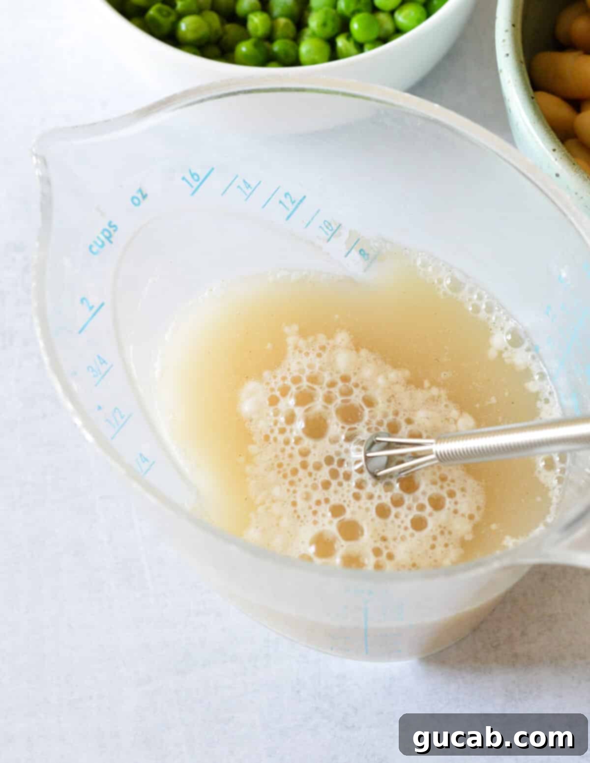 Vibrant Veggie Noodle Bowl 6 A measuring cup containing vegetable stock mixed with all-purpose flour, creating a slurry to thicken the soup.