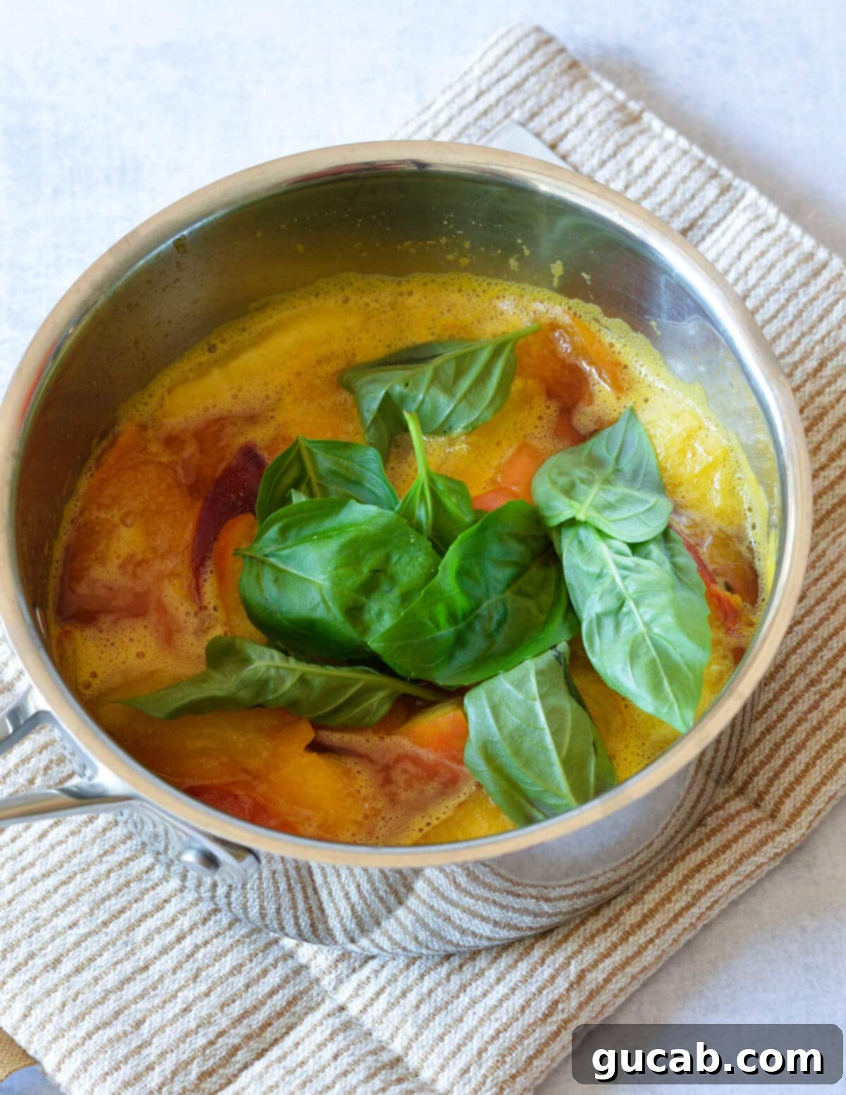 a pot with cooked peaches and basil in it. 