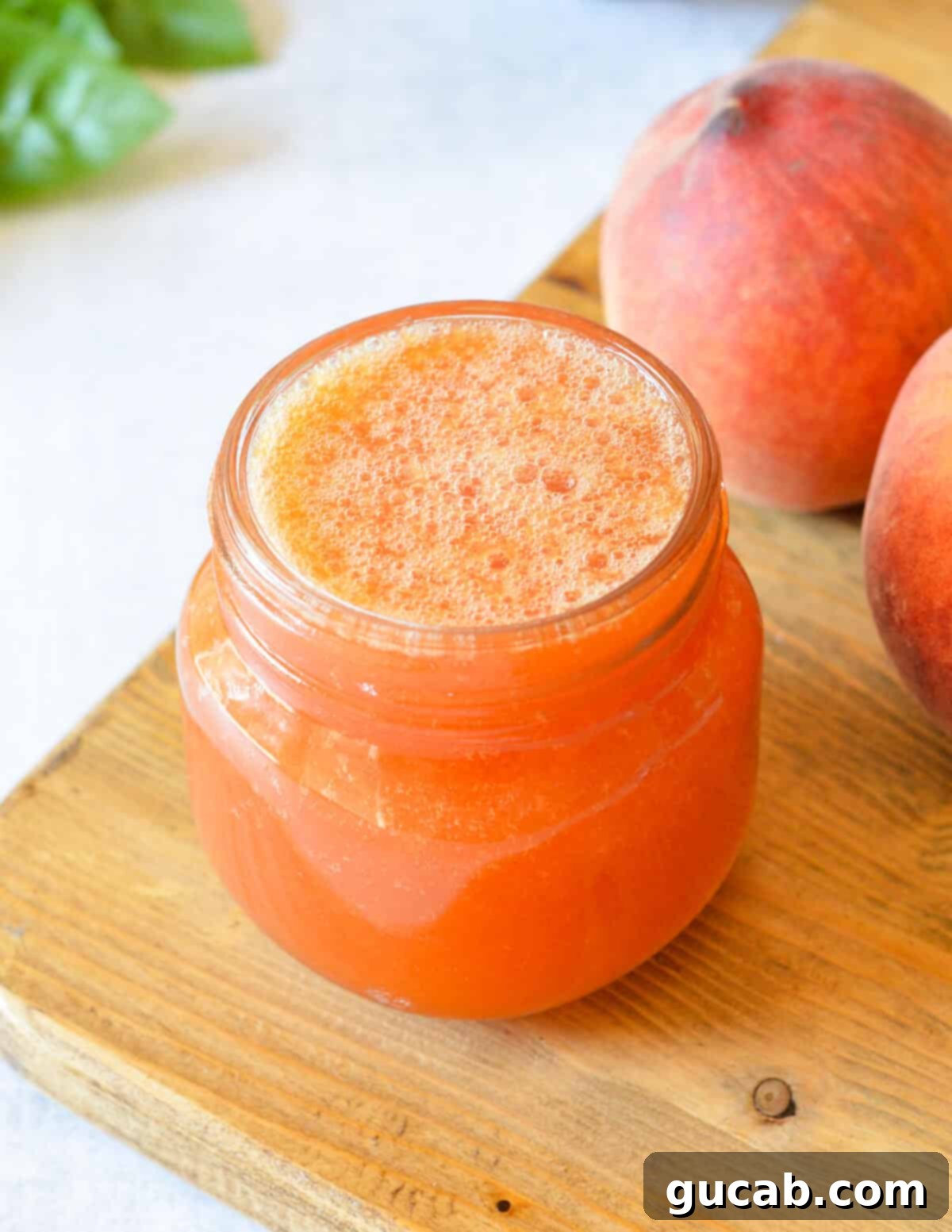 a jar of peach syrup with bubbles on top. 