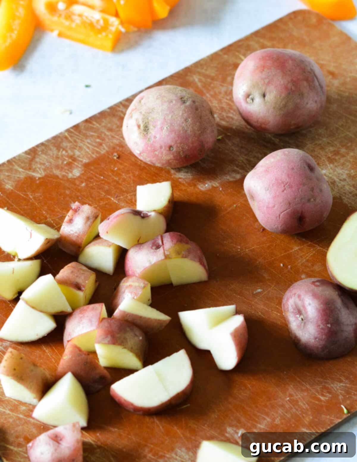 Red potatoes expertly cut into small, uniform chunks, ready for roasting on a sheet pan.
