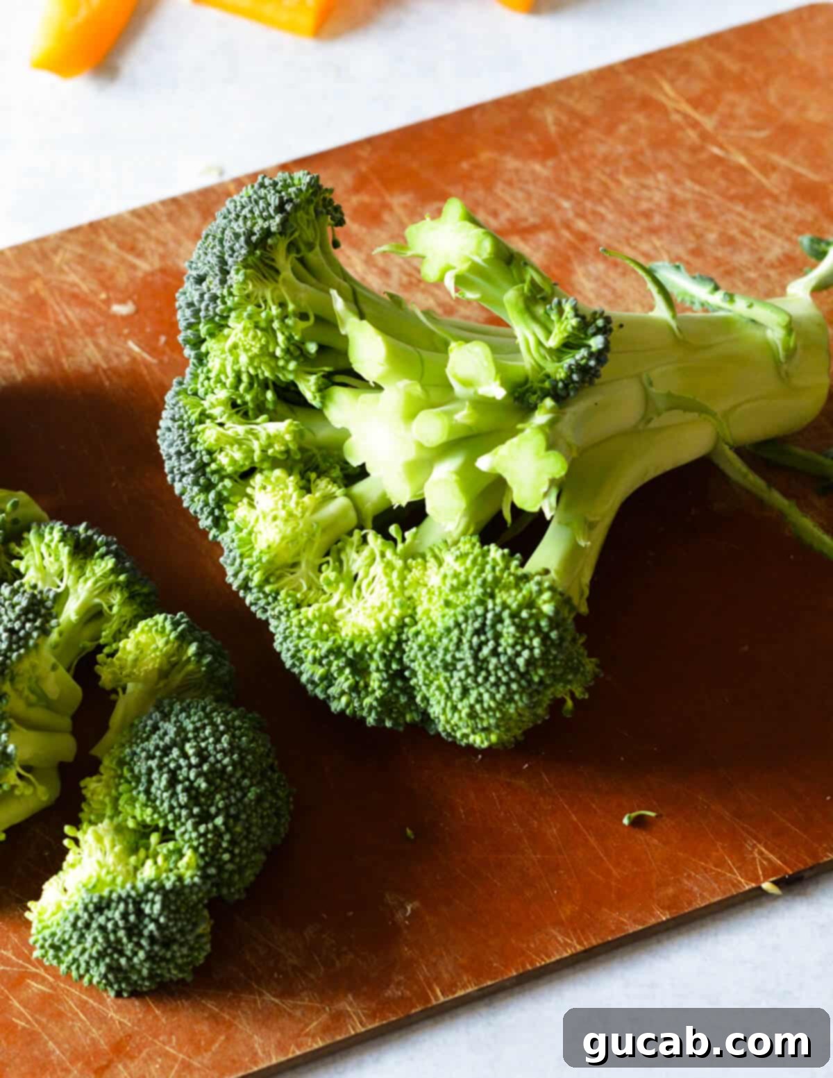 A hand skillfully cutting a head of broccoli into small florets for even cooking in a sheet pan dinner.