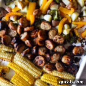 A sheet pan showcasing crispy corn ribs, perfectly caramelized chicken sausage, and a colorful mix of roasted bell peppers, broccoli, and potatoes, all cooked together for a wholesome meal.