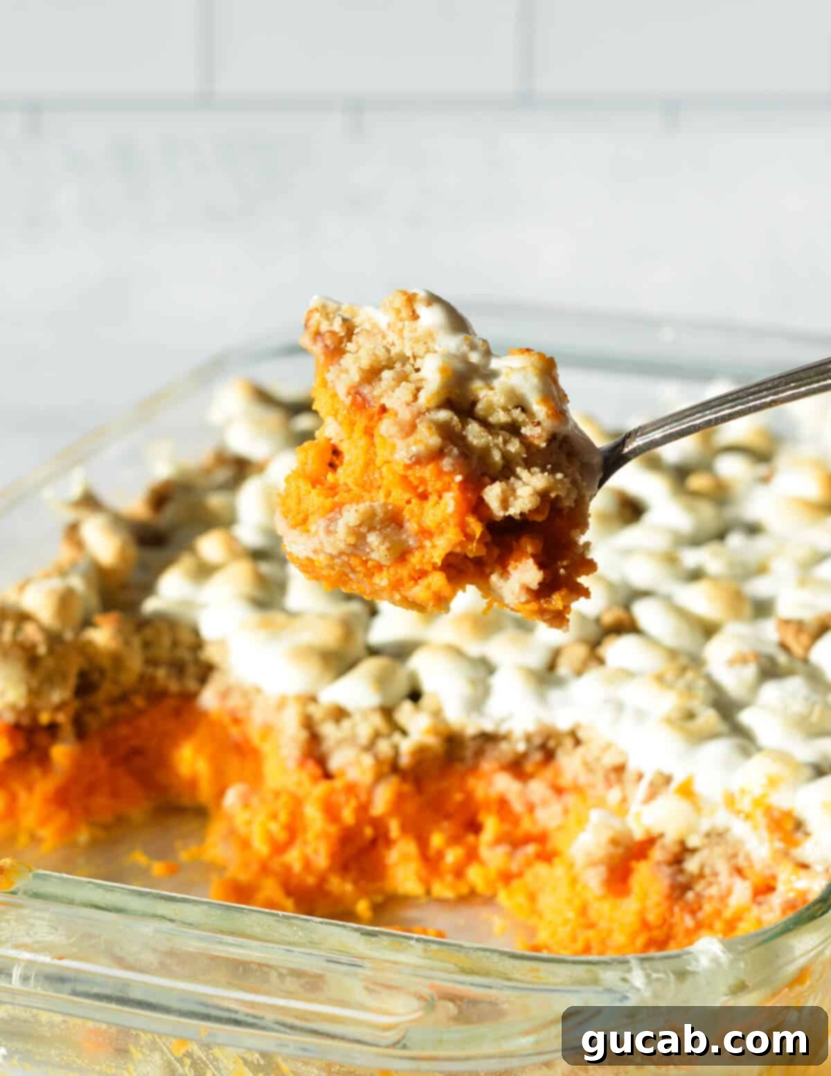 Deliciously Gluten-Free Thanksgiving: 19 Must-Try Recipes 6 A large serving spoon scooping out creamy sweet potato casserole, revealing its rich texture and delicious streusel topping, a perfect gluten-free Thanksgiving side.