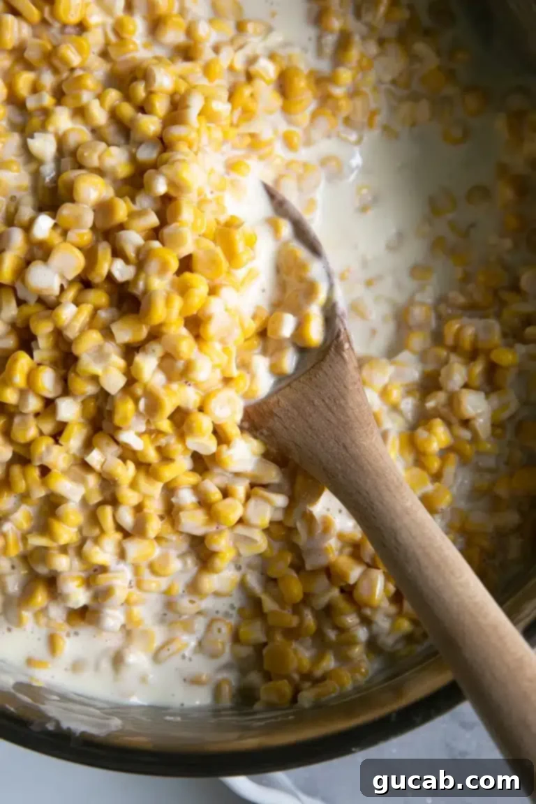 Deliciously Gluten-Free Thanksgiving: 19 Must-Try Recipes 9 A wooden spoon resting in a pot of rich, creamy homemade creamed corn, showcasing its inviting texture, a simple yet beloved Thanksgiving side dish.