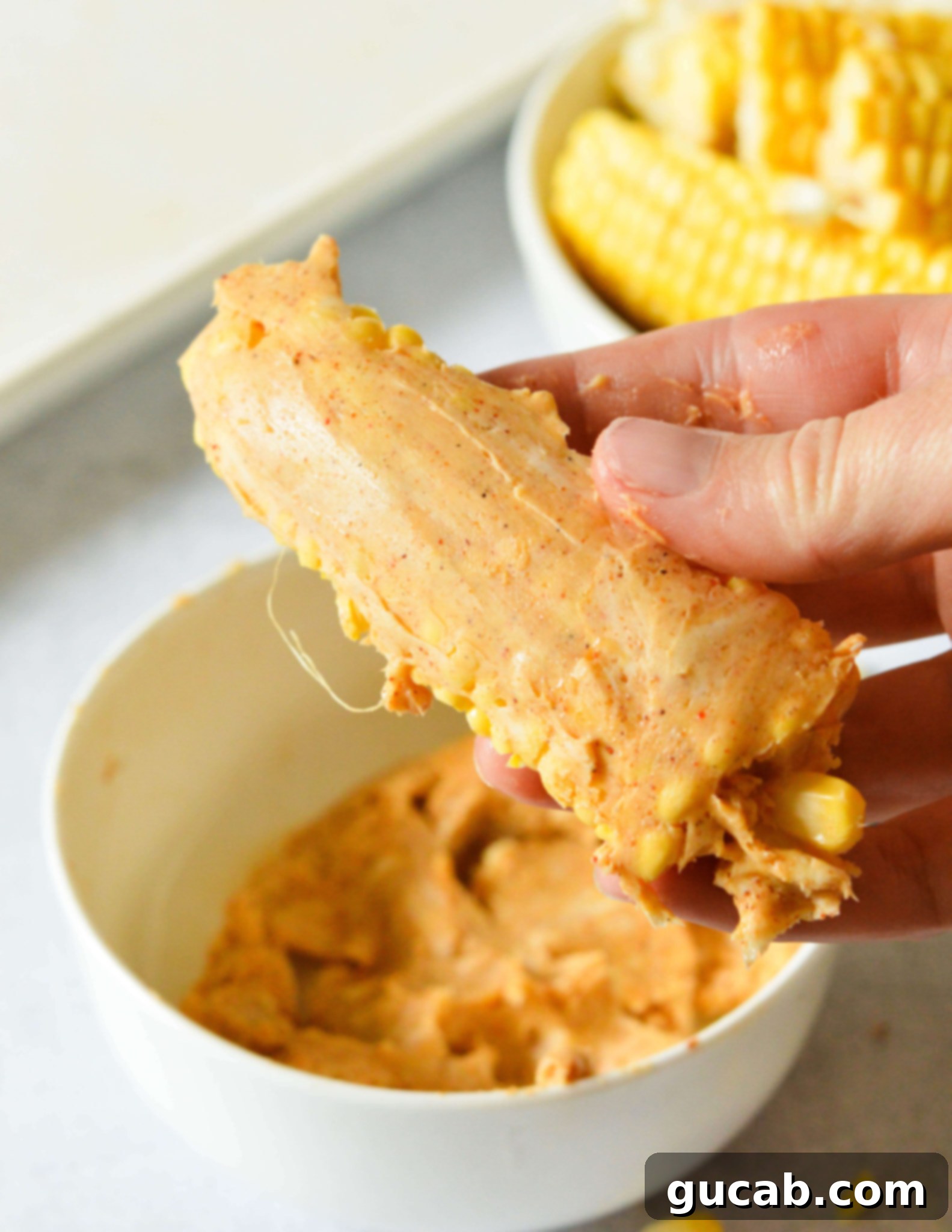 hand holding a corn rib slathered in chili butter.