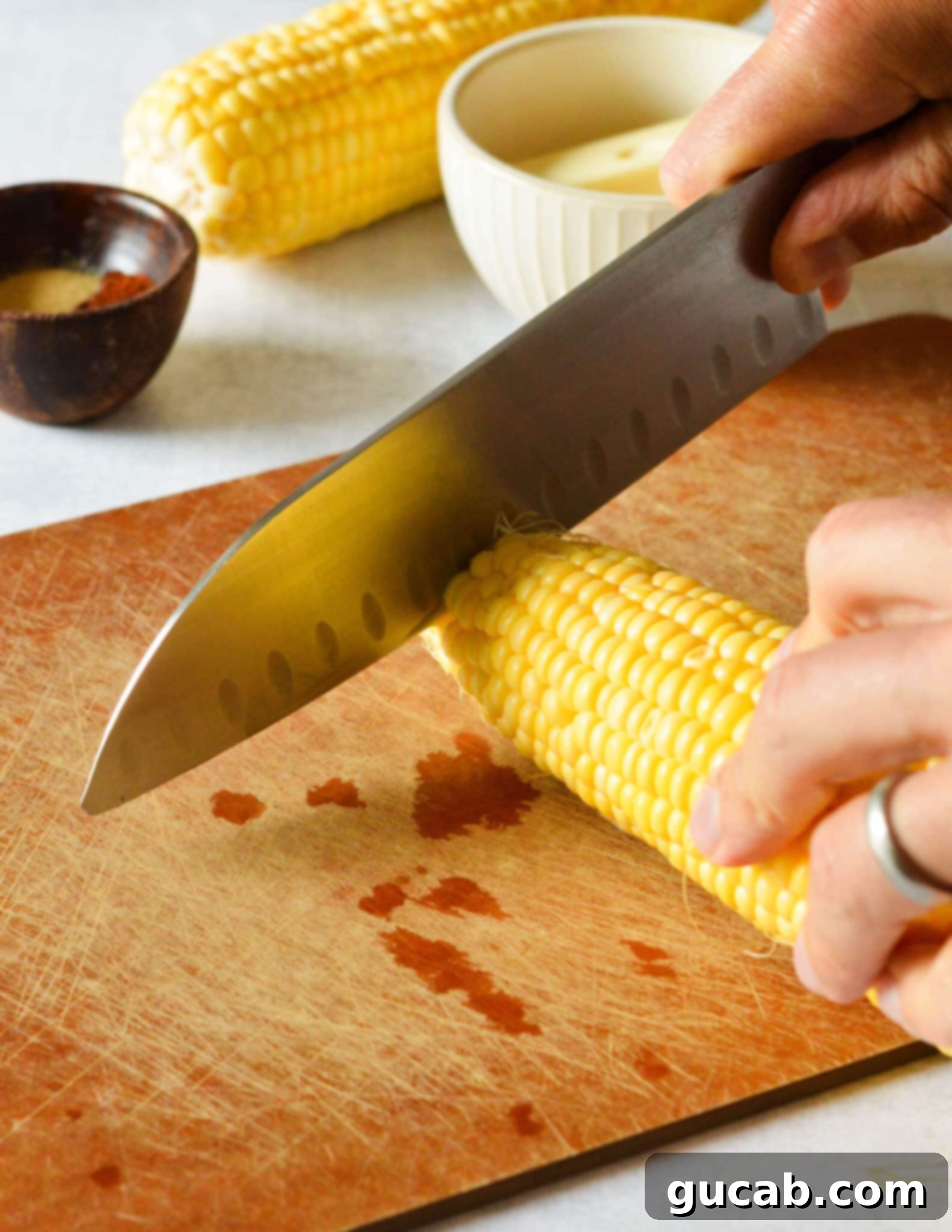 knife cutting the top off a corn cob.
