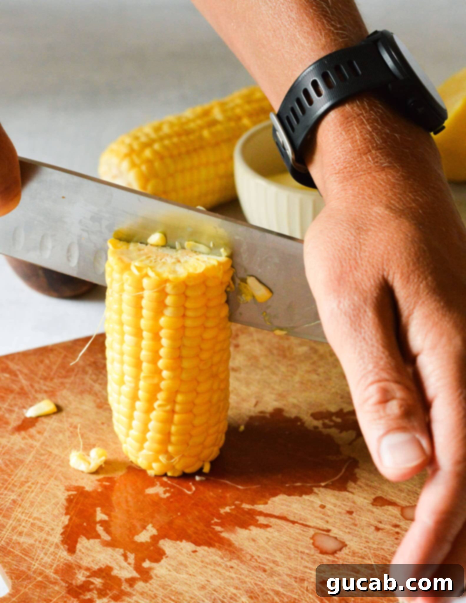 knife going through a standing corn rib on a cutting board. 
