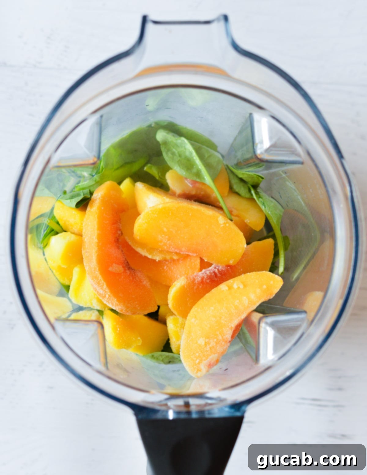 Panera's Emerald Zest Smoothie 4 Frozen peaches, frozen mango, and spinach carefully layered in a blender, ready for blending.